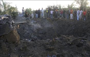 فلسطينيون يعاينون الدمار الذي خلفته إحدى الغارات الإسرائيلية على بلدة دير البلح في وسط قطاع غزة أمس