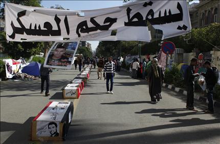مصريون قرب مجسمات لنعوش ملفوفة بالعلم المصري خلال تظاهرة أمام مقر الحكومة في القاهرة أمس (أ ب) 
