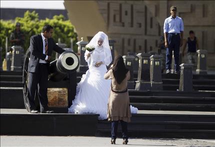 مصرية تلتقط صوراً لعروسين أمام نصب الجندي المجهول بالقرب من إشارة «رابعة العدوية» شرقي القاهرة أمس (رويترز) 