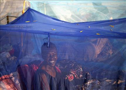 إمرأة تجلس داخل خيمة ضد البعوض قرب أحد مراكز الاقتراع في أبيي أمس (رويترز) 