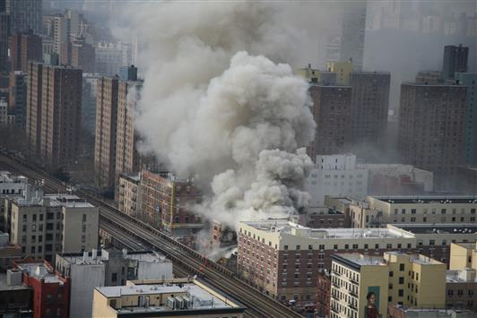 الدخان يتصاعد من مكان انهيار المبنى في هارلم في نيويورك أمس (رويترز)