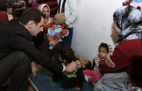 الرئيس السوري بشار الاسد أثناء تفقّده العائلات النازحة في مركز الدوير في عدرا أمس (سانا)