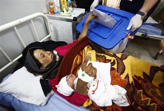 إمرأة عراقية تشارك في العملية الانتخابية من على سريرها في أحد مستشفيات مدينة النجف أمس (رويترز)