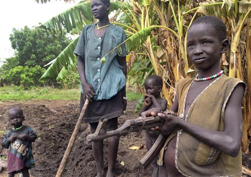 فتى مع عائلته يلهو ببندقية وجدها مدفونة في الأرض في بلدة نيال في جنوب السودان(أ ب)