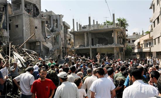 سوريون يتفقدون الدمار الناتج عن انفجار سيارة في حي كرم اللوز في حمص امس (ا ب ا)