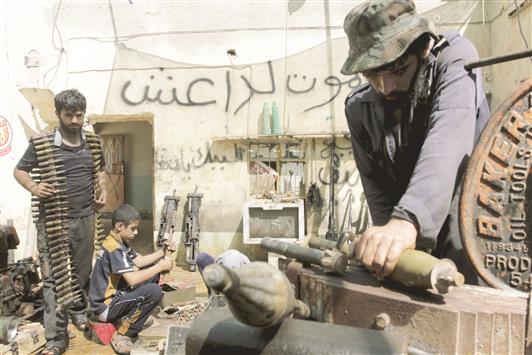 متطوعون في ورشة اصلاح أسلحة لـ«الحشد الشعبي» في البصرة، أمس (رويترز)