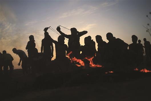 فلسطينيون يرشقون جنود الاحتلال بالحجارة عند الجدار الامني قرب مخيم البريج في قطاع غزة، امس (ا ف ب)