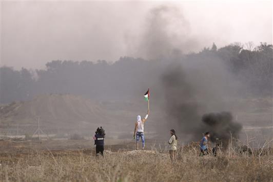 فلسطينيون في مواجهات مع قوات الاحتلال عند الشريط الامني قرب مخيم البريج في قطاع غزة امس (ا ف ب)