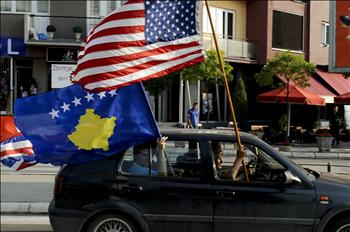ألبان من كوسوفو يجولون بسيارة رافعين علماً أميركياً وآخر لدولتهم المعلنة من طرف واحد في عاصمة الإقليم بريشتينا أمس