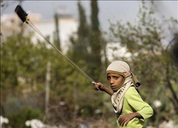 فتى فلسطيني يستخدم المقلاع لرمي الحجارة على جنود الاحتلال خلال تظاهرة في بلدة نعلين في الضفة أمس