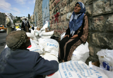 فلسطينية تراقب تسليم مساعدات من الأونروا في الخليل أمس